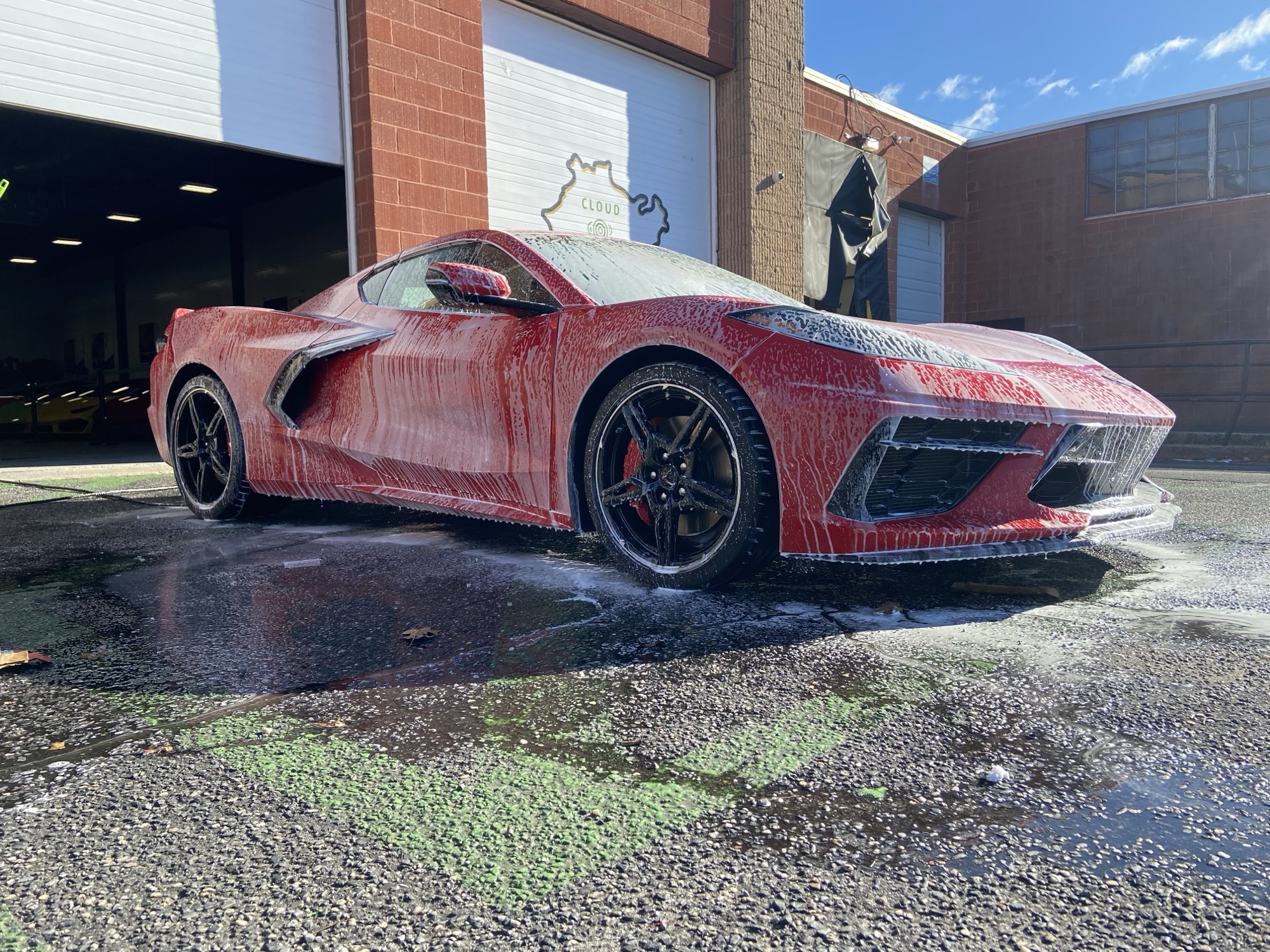 Red Corvette C8 covered in foam during a hand wash